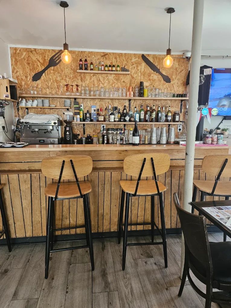 Le bar de L'Ardoise Occitane, ses tabourets et la fourchette et le couteau de l'enseigne au mur